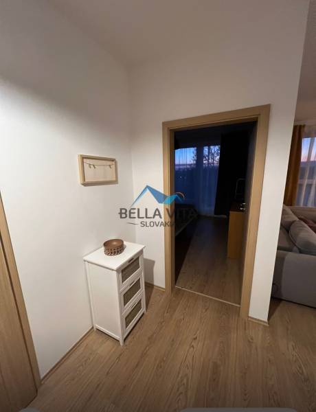 Interior of a 2-room apartment with a wooden decor floor, light furniture and decorations.