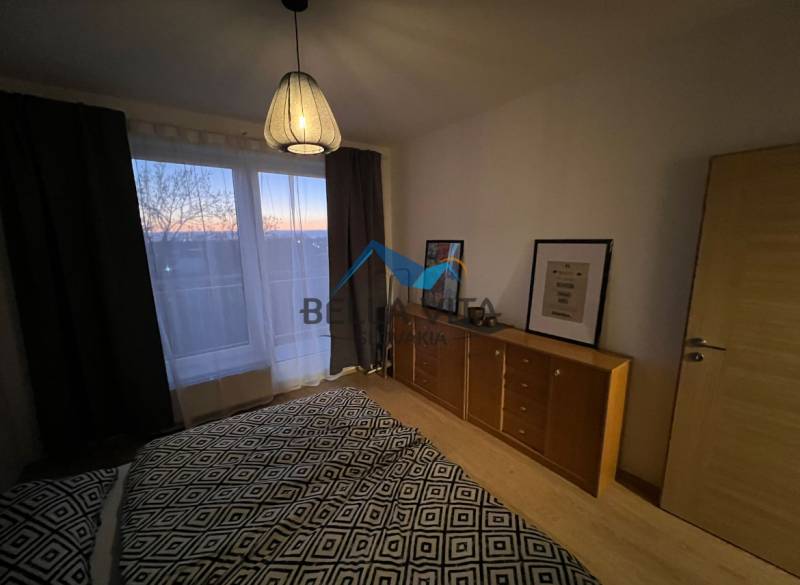 Bedroom with a dresser and a lamp, wooden decor flooring in a 2-room apartment.