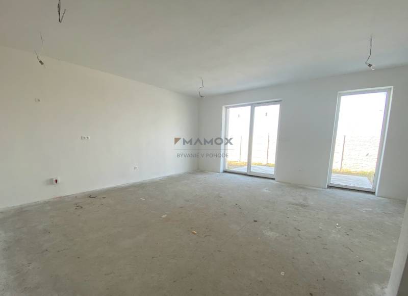 A spacious room in a family house with a concrete floor and large windows.