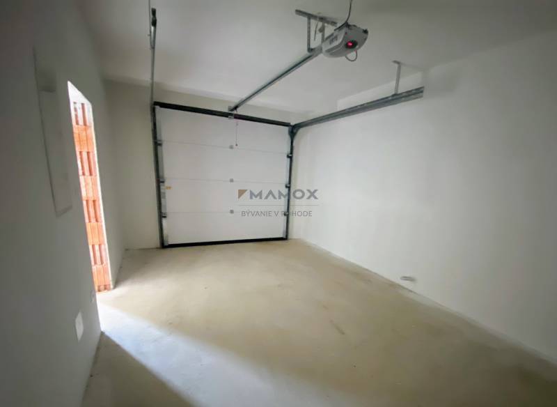 A garage with white walls and an electric gate in a family house.