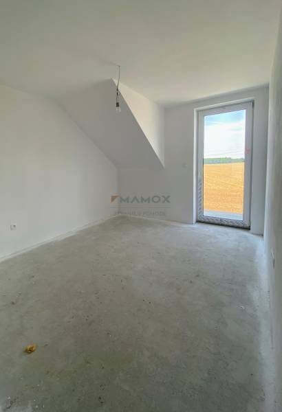 An empty room in a family house with a concrete floor and a skylight overlooking the fields.