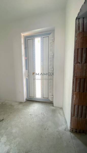 Entrance door in the interior of a family house with a concrete floor and an unplastered brick wall.