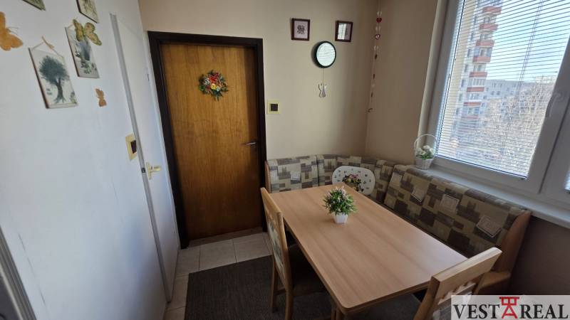 Dining area with a table and benches in a 3-room apartment.