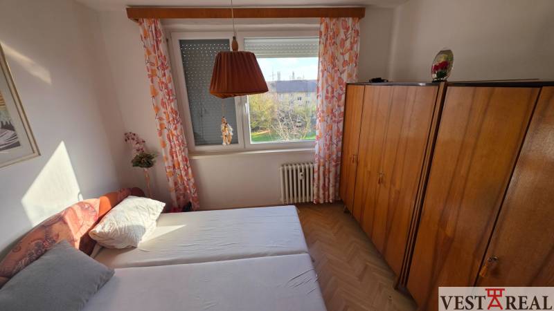 A bedroom with a bed, wardrobe, and wooden decor flooring in a 3-room apartment.