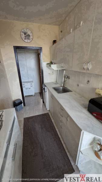 A kitchen in a 3-room apartment with a long countertop and light cabinets.