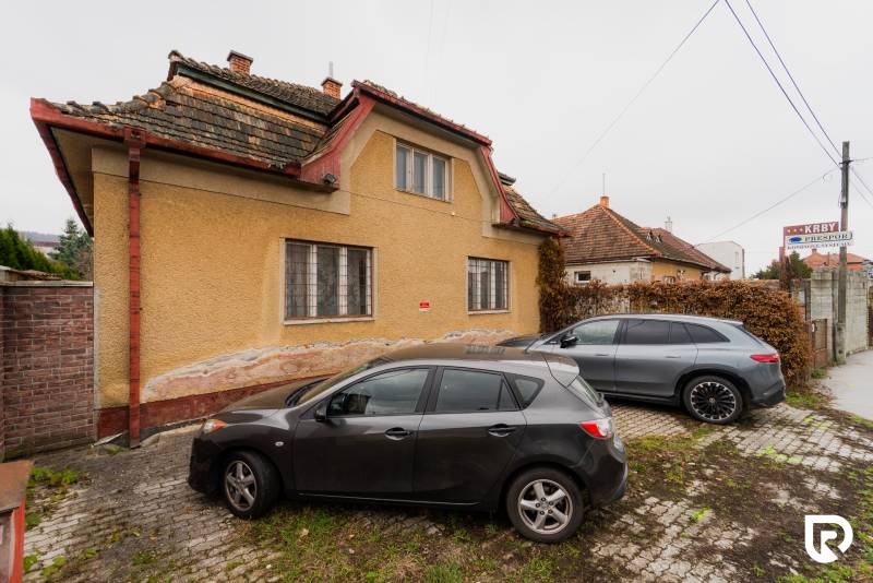 A family house on Partizánska Street in Bánovce nad Bebravou with two cars parked in front of it.