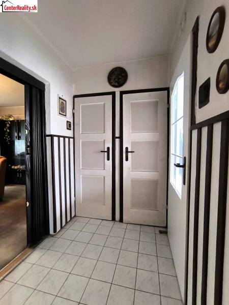 Interior of a family house with white doors, tiles, and dark wall cladding.