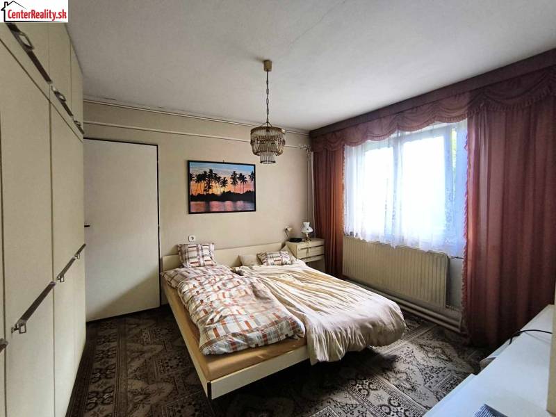 Bedroom in a family house with a bed, wardrobe, and a picture on the wall.