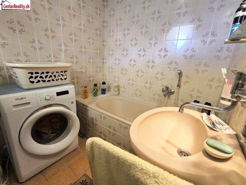 Bathroom in a family house with a bathtub, washing machine, and sink.