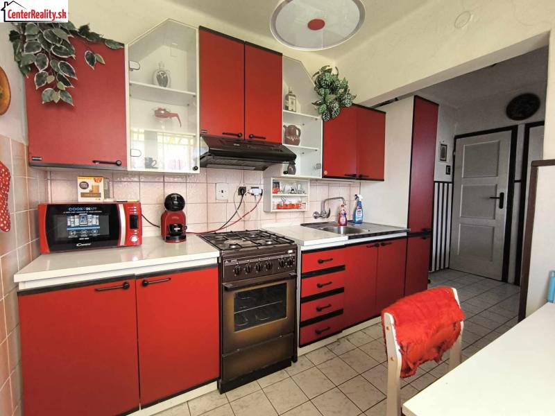 Red kitchen in a family house with a microwave and a stove.