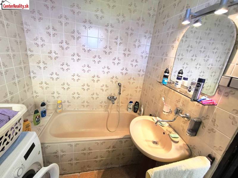 Bathroom with a bathtub and a washing machine in a family house with tiles.