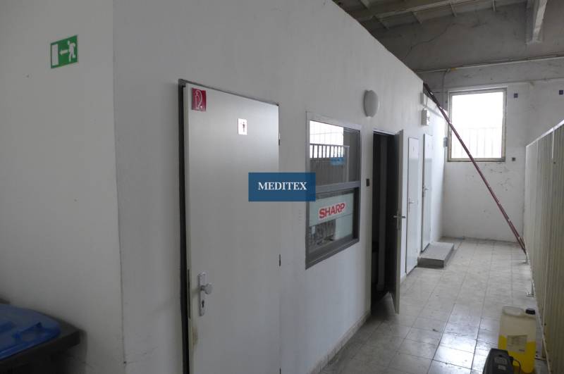 Interior with white doors and gray walls in warehouse and hall spaces.