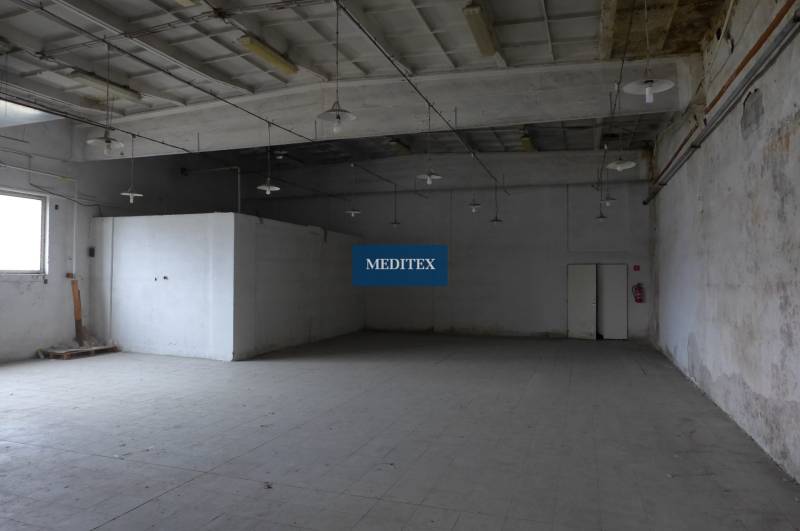 Industrial warehouse interior with high ceiling and concrete floor.