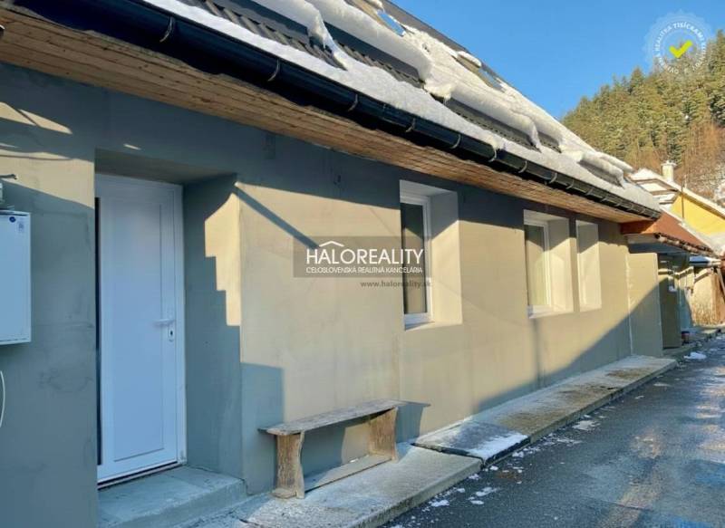 A family house in Hronec with snow on the roof, white doors, and a wooden bench.