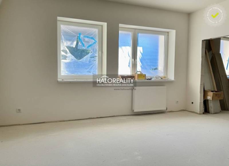 A room in a family house with windows and a radiator, unused space ready for completion.