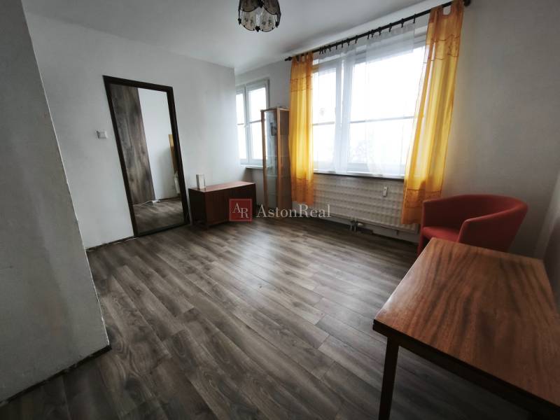 Living room in a studio apartment with a wood-patterned floor and yellow curtains.