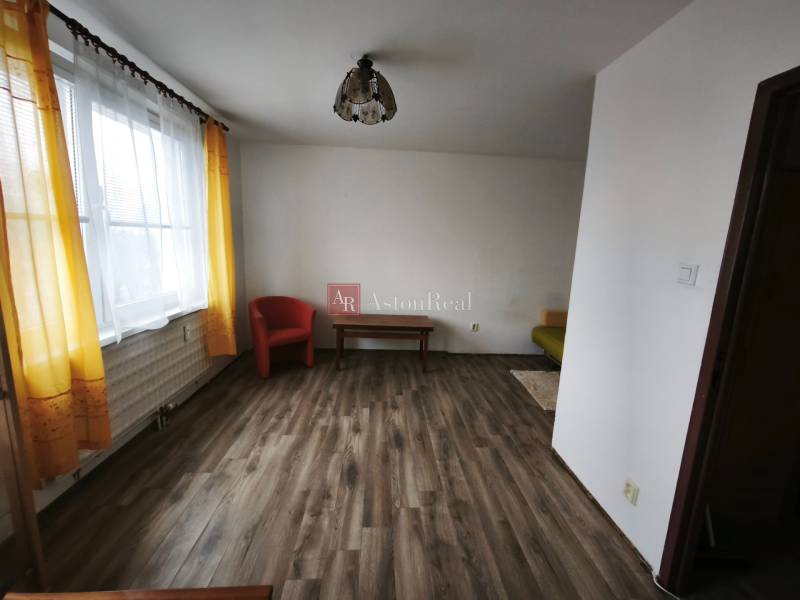 Living room in a studio apartment with wood-patterned flooring and yellow curtains.