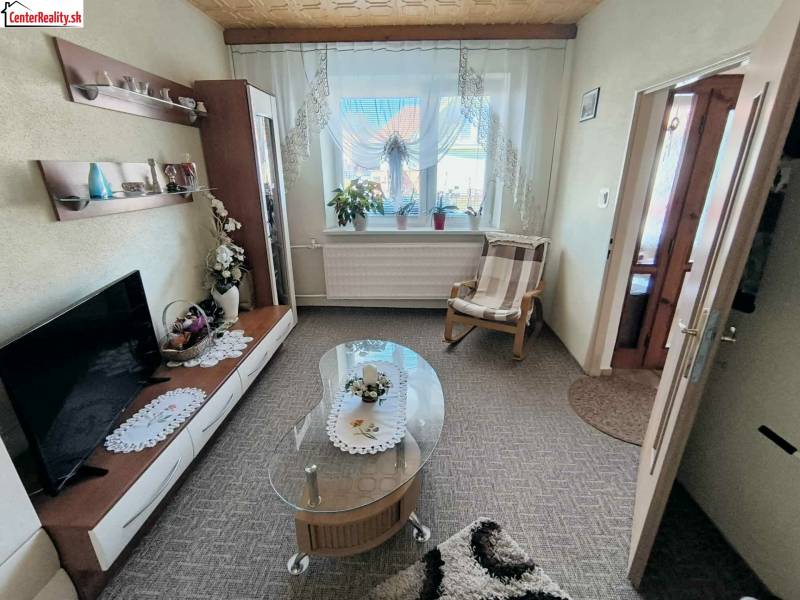 Living room in a family house with a carpet, television, and glass table.