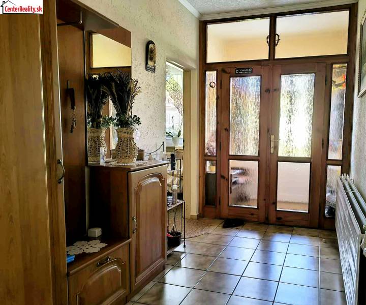 A hallway in a family house with a mirror, decorations, and glass doors.