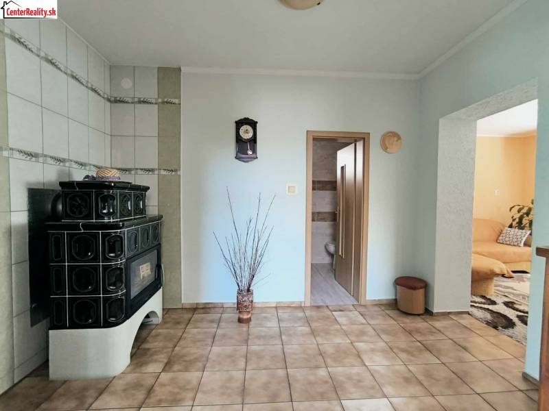 Interior of a family house with green tiles, a tiled stove, and paving.