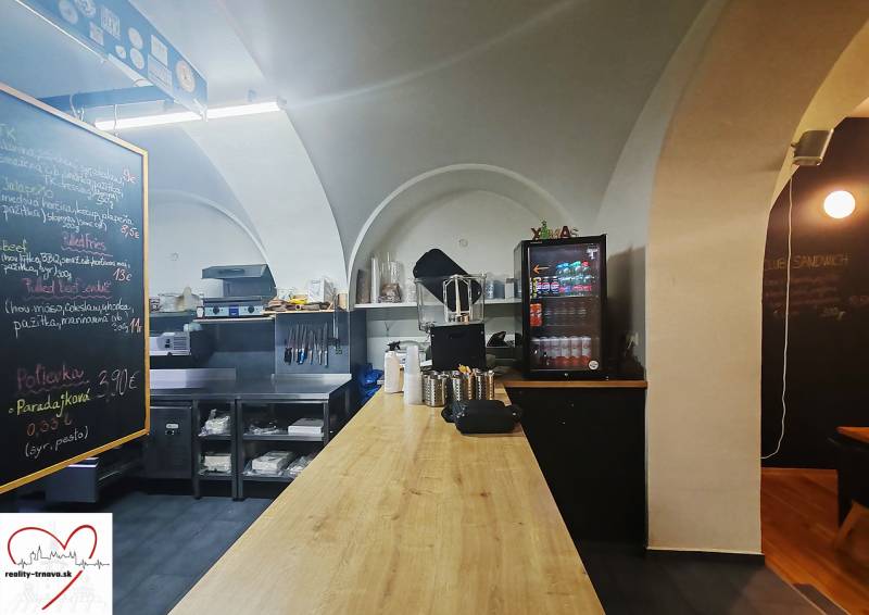 Interior of a gastro space with wood-decor flooring, a worktop, and beverage cooling.