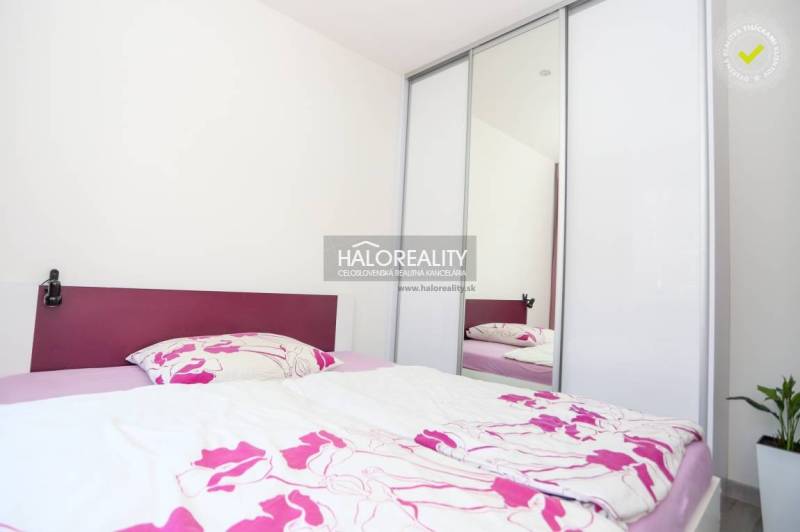 Bedroom in a 2-room apartment with a bed and wardrobe, bright interior, flowers on the duvet.