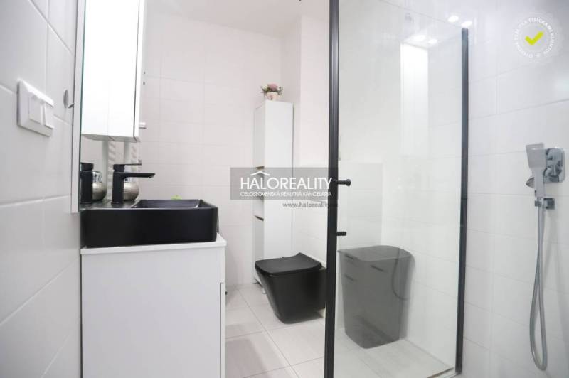 Modern bathroom in a 2-room apartment with black accessories and a shower, elegant design.