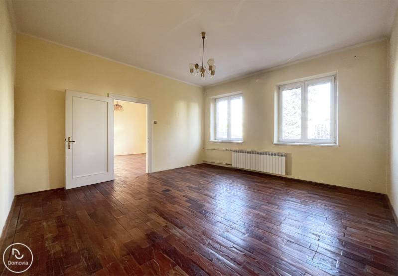 A spacious room with a wooden-decor floor and two large windows.