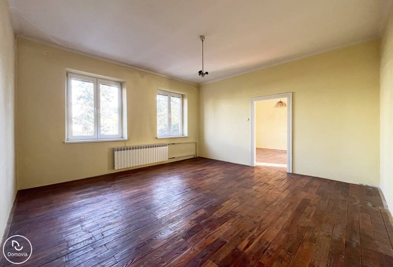 A room with two windows, light-colored walls, and a wooden decor floor in a 5 or more room apartment.