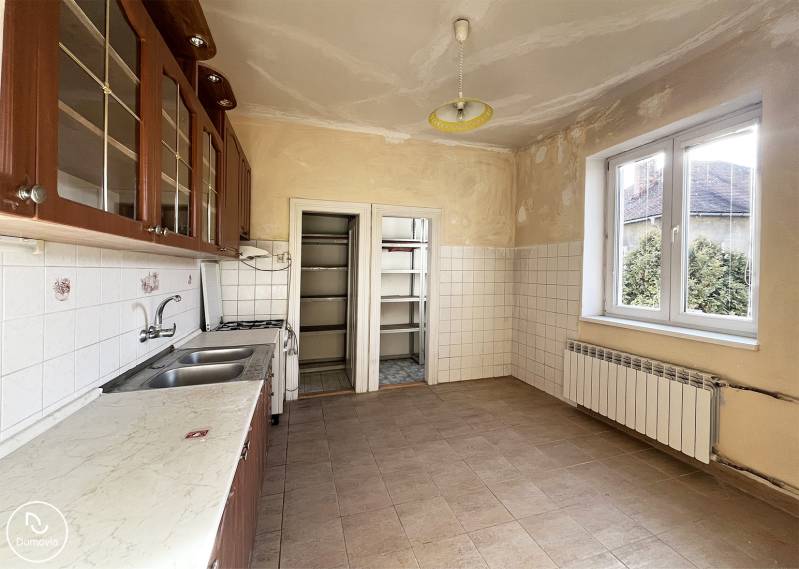 A kitchen in a 5 or more room apartment with tiles, wooden cabinets, a gas stove, and a sink.