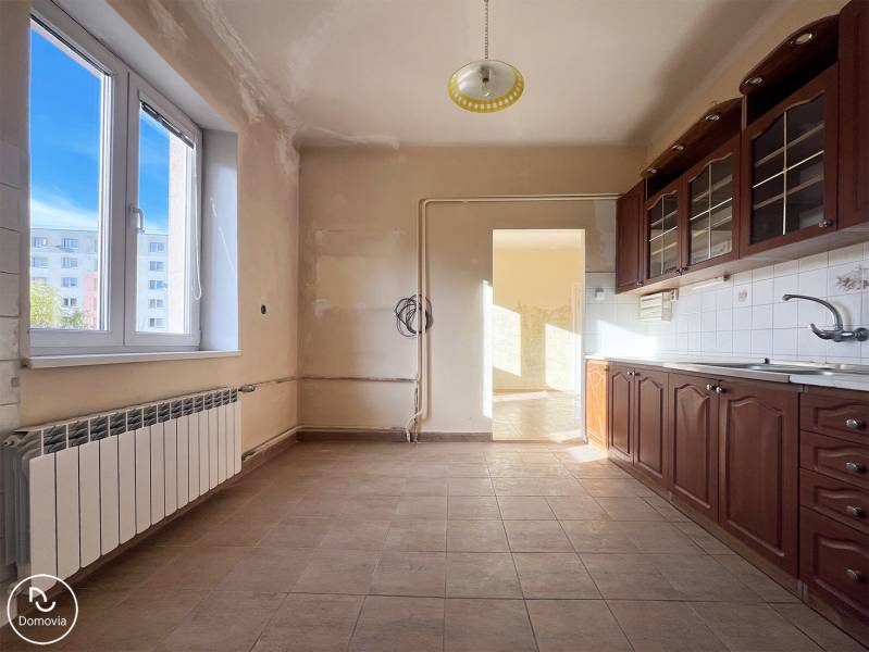 A kitchen in a 5 or more room apartment with a wooden decor and a large window.
