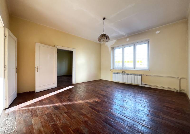 A room in a 5 or more bedroom apartment with a wood-patterned floor and large windows.