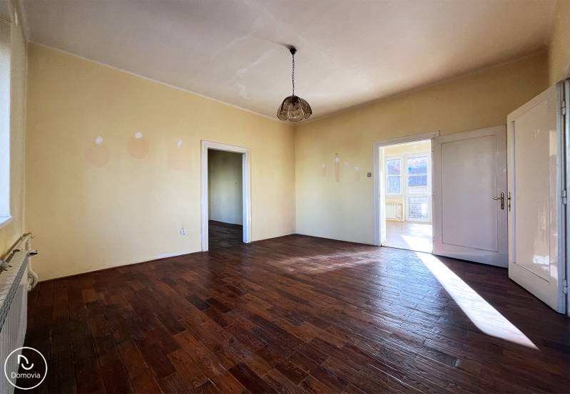 A room with a wooden decor floor and light walls in a 5 or more room apartment.