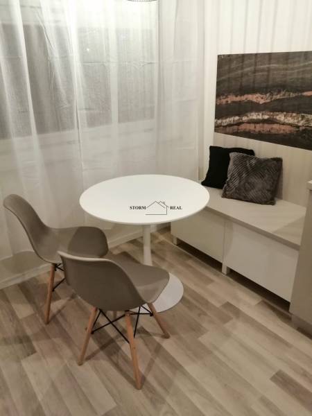 Dining nook with a round table, two chairs, and decorative cushions, floor with wooden decor.