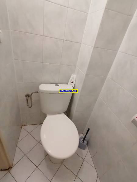 A restroom in an office with white tiles and flooring.
