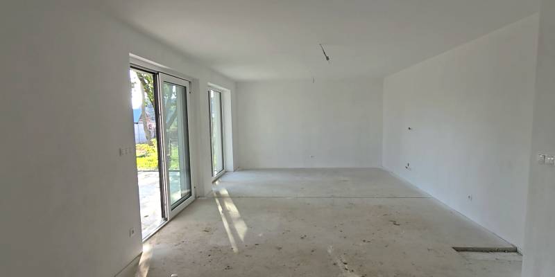 A spacious room in a family house with large windows and a concrete floor.