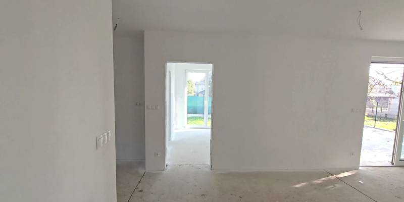 A family house with a bright room, white walls, and large windows overlooking the garden.