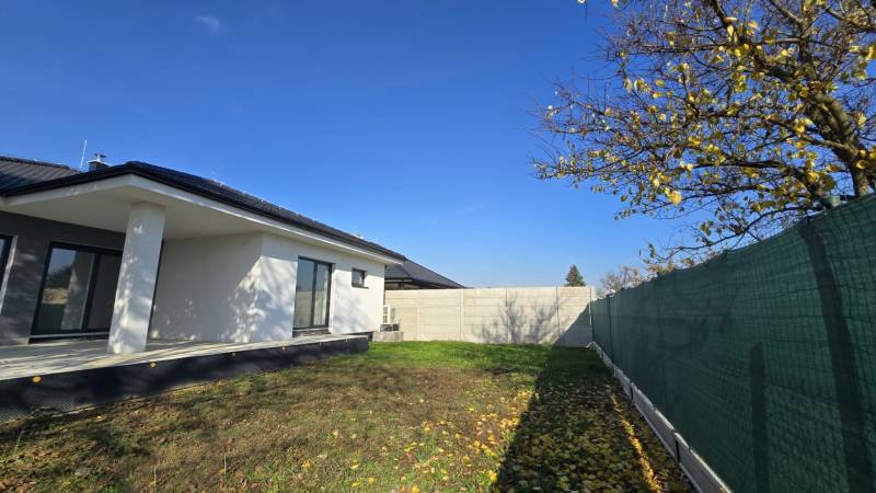 A family house in Piešťany with a garden, fencing, and a blue sky.