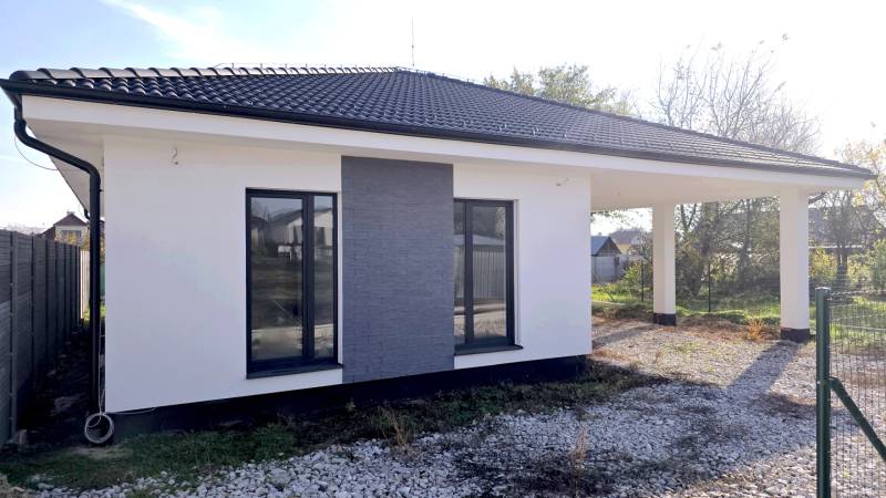 A family house in Piešťany with a white facade, dark roof, and gravel driveway.