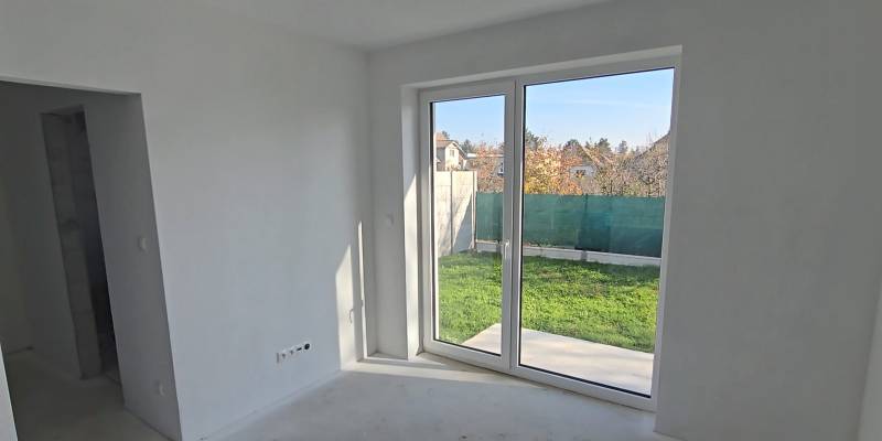 Interior of a family house with a large window to the garden, white walls and floor.