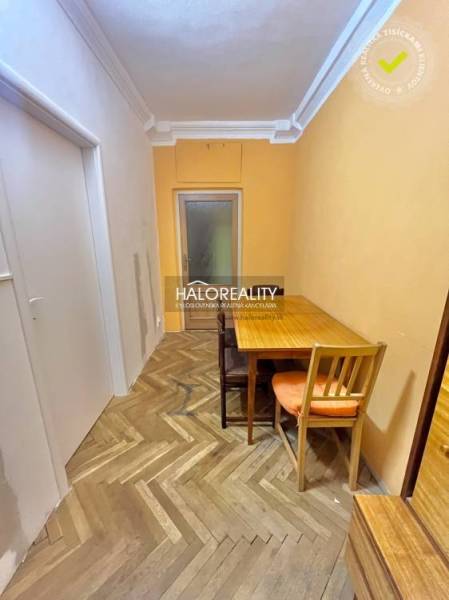 A narrow corridor with a table and chairs, a floor with a wooden decor in a 4-room apartment.