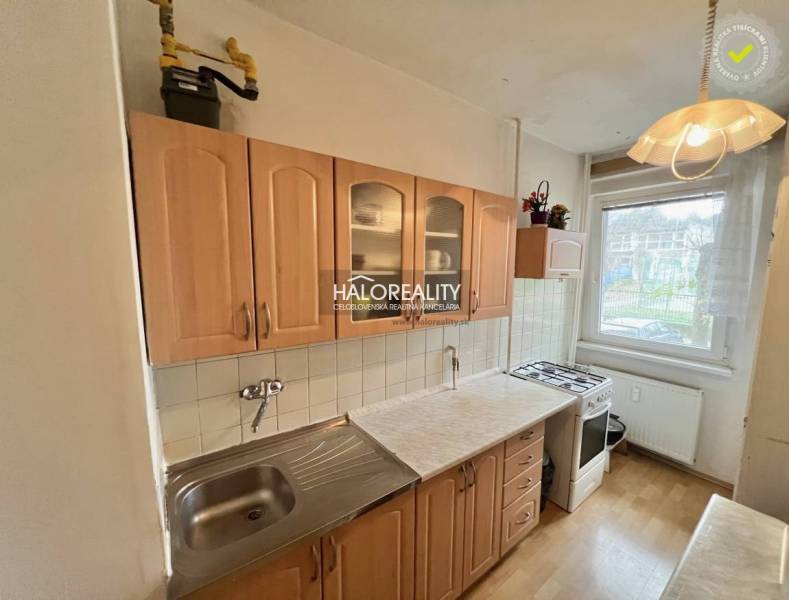 A kitchen in a 4-room apartment with wooden decor cabinets and a gas stove.