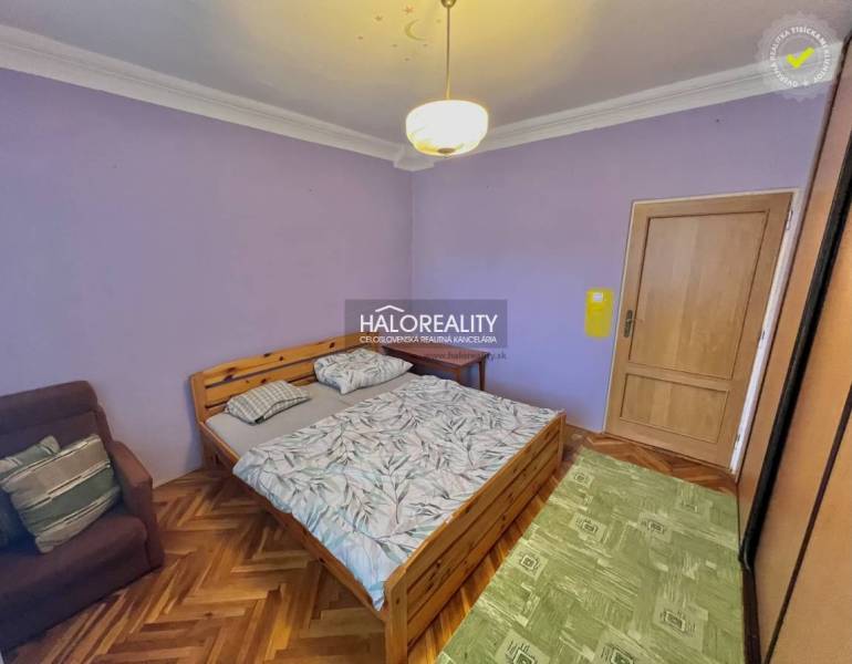 A bedroom in a 4-room apartment with a wooden decor floor and purple walls.