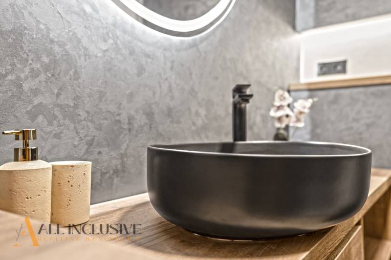 A bathroom in a 2-room apartment with a stylish sink and a decorative wall.