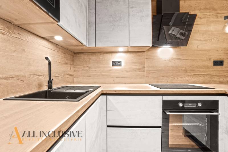 A kitchen in a 2-room apartment with a countertop and wall with a wood decor.