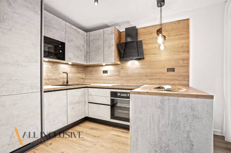 A kitchen in a 2-room apartment with a wood-decor floor and wood paneling.
