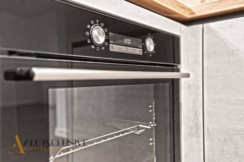 An electric oven in the kitchen of a two-room apartment with a wooden decor floor.