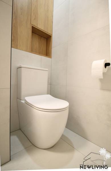 Toilet with wooden decor, shelves, and tiles in a studio apartment.