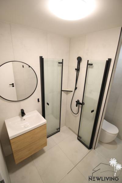 Bathroom in a studio apartment with a glass shower enclosure and minimalist design.