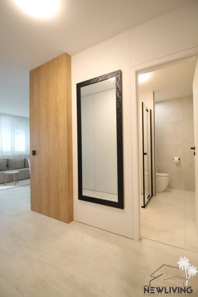 A hallway with a large mirror and a bathroom in a studio apartment. Floor with wood decor.